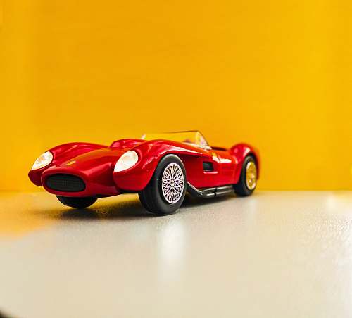 machine red coupe scale model on white surface spoke